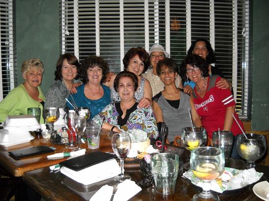 A group of friends enjoy each other's company at a restaurant, sharing drinks and laughter.