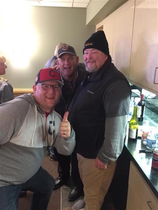 Group of friends posing with smiles and thumbs up in a warm indoor environment during winter.