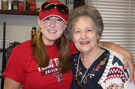 Two women smile happily together, showcasing their connection and joy at a university gathering.
