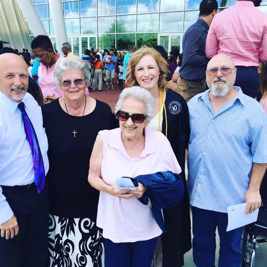 Group of five people poses joyfully after a graduation event, showcasing smiles and celebration.