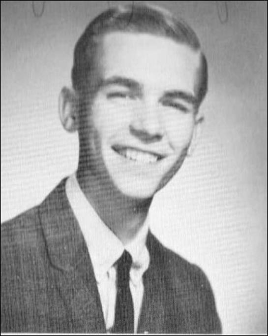 A cheerful young man in a 1960s suit and tie flashes a charming smile.