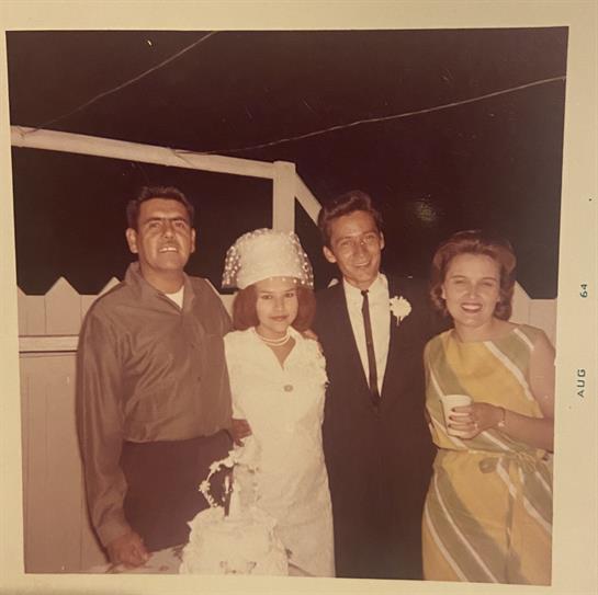 Four friends enjoy a festive evening together, sharing laughter and drinks in a cozy backyard.