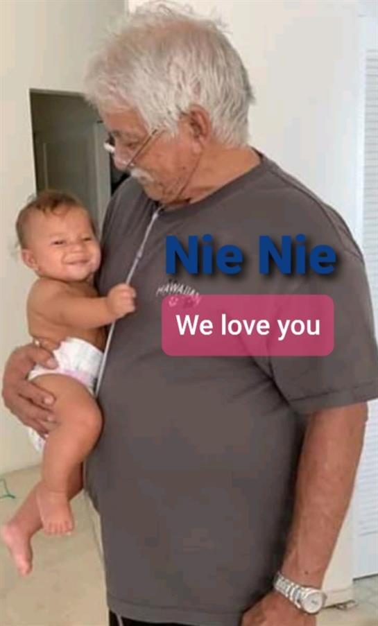 A joyful grandfather hugs his happy baby, both radiating warmth in a cozy home.