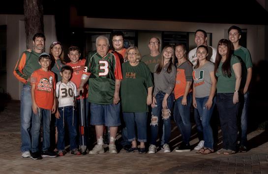 A large family outdoors in jerseys and casual wear enjoys a nighttime gathering.