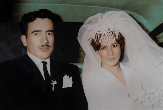 A couple dressed in elegant wedding attire sits side by side, showcasing timeless fashion and joy.