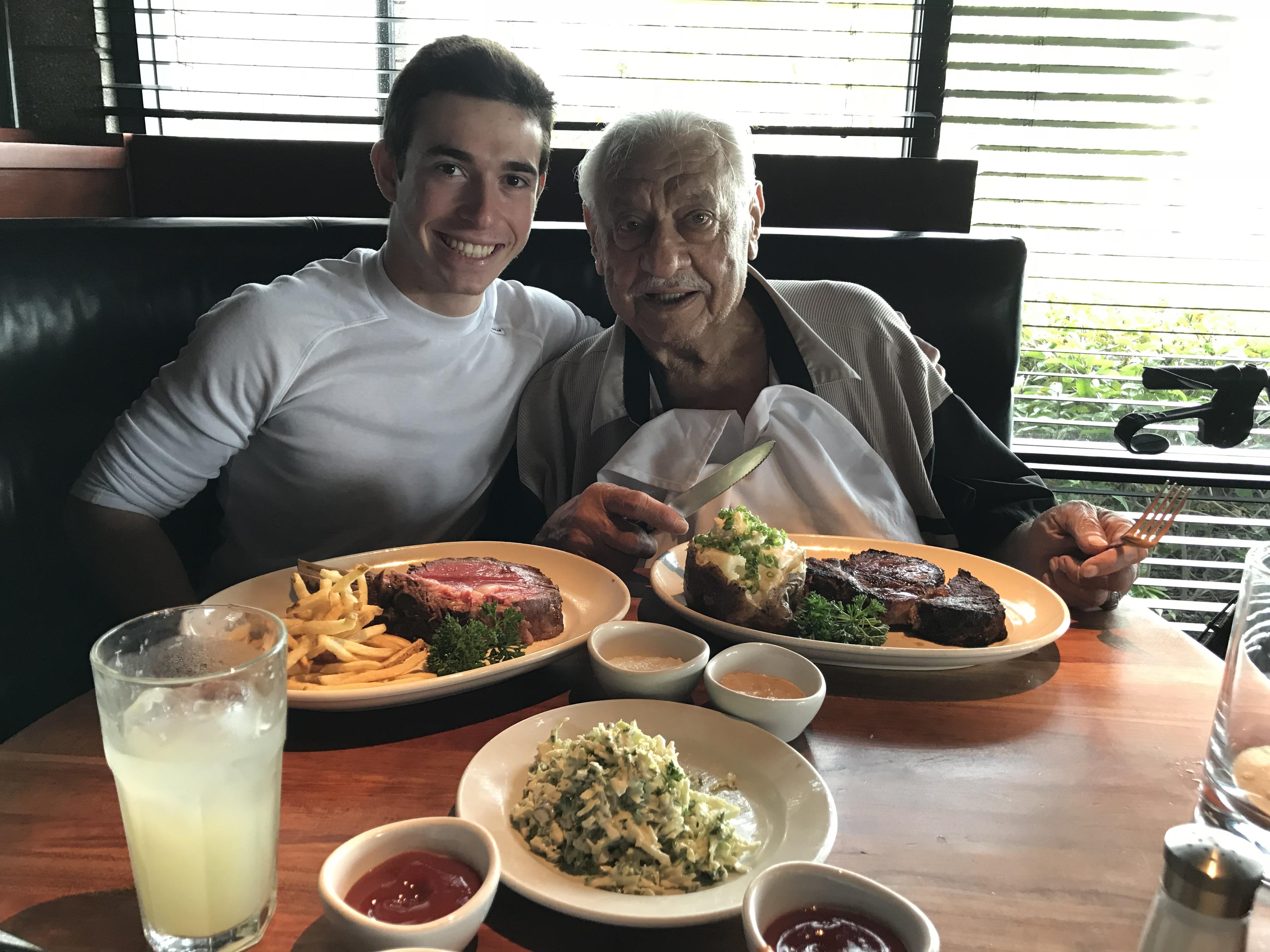 A man and a young man sitting at a table with plates of food