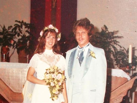 Newlyweds in formal wear smile with a bouquet on their wedding day.