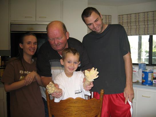 Family members enjoy a cheerful moment in the kitchen as a boy proudly displays his creations.