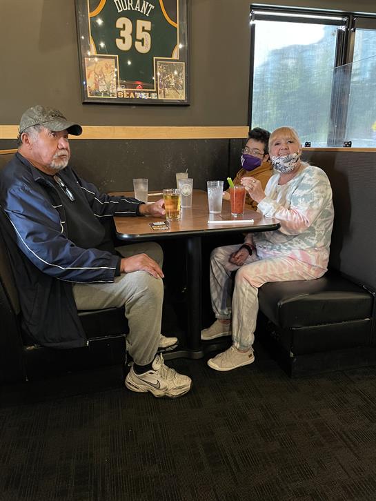 Friends sharing a meal at a booth, enjoying each other's company in a relaxed atmosphere.