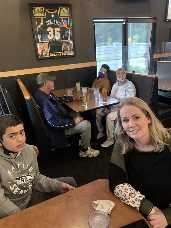 Friends and family relax in a restaurant booth, sharing drinks and engaging in conversation.