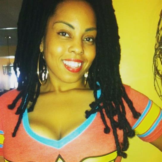 A woman with long hair wearing a bold costume smiles warmly, showcasing her joyful personality.