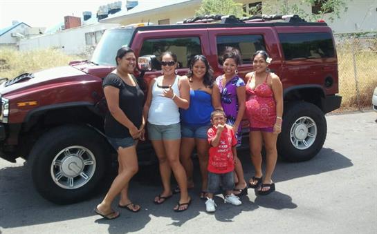 Six friends smile and pose for a picture together in front of a large vehicle on a warm day.