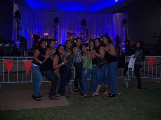 Friends gather for a festive celebration under colorful lights and music during nightfall.