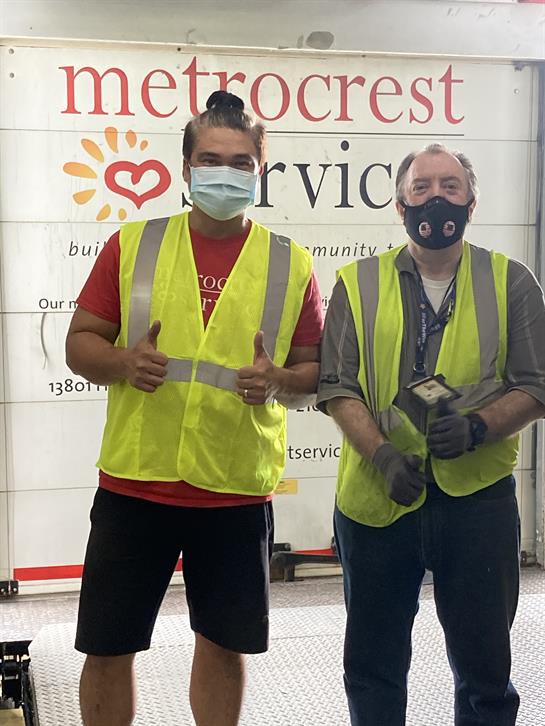Two volunteers give thumbs up while participating in community service at Microcrest Services.