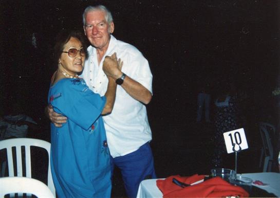 A happy couple dances amid vibrant decor and a lively crowd at a night event.