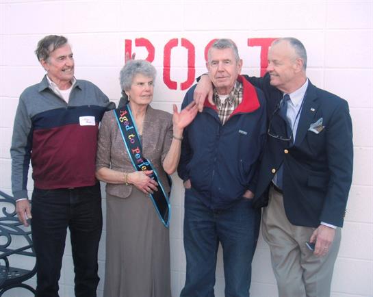 Four friends gather outdoors, sharing smiles and laughter at a community gathering.