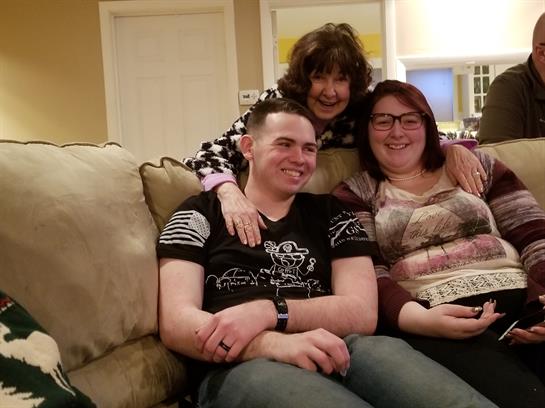 Three friends share smiles and laughter while sitting comfortably on a couch in a cozy living room.