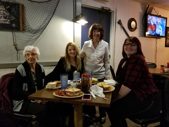 Four women gather around a table sharing a meal in a warm, inviting atmosphere.