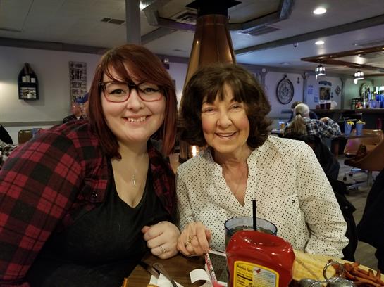 Two women share a joyful moment at a restaurant, smiling while enjoying their meal together.