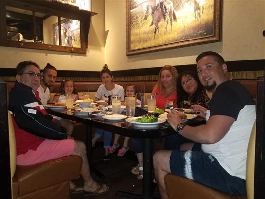 A group of friends shares a lively dinner around a large table filled with food and drinks.