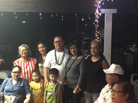 A joyful gathering of family and friends captures shared moments under sparkling lights at night.