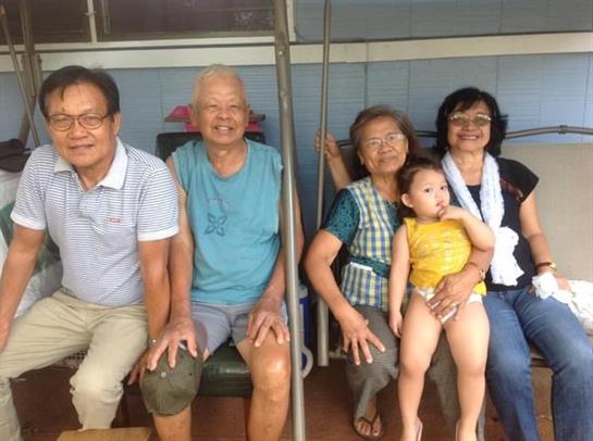 Family members smile and relax on a porch during a sunny afternoon gathering, sharing laughter.