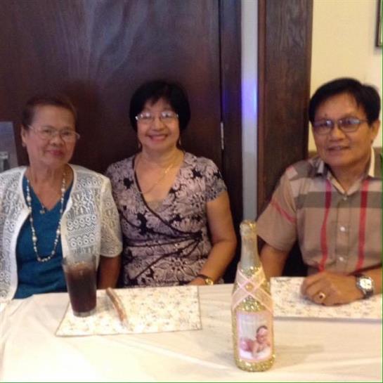 Three friends smile and relax together while sharing drinks at a friendly gathering.