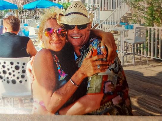 Two people embrace joyfully at a resort, surrounded by bright colors and a relaxed atmosphere.