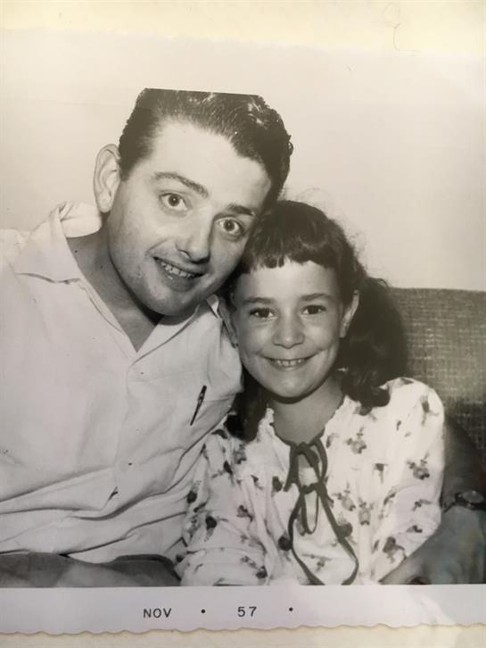 A man and a girl share a joyful moment on a couch in a warm, inviting living room.