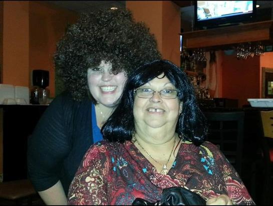 Two women pose together at a restaurant, showcasing vibrant hairstyles and joyful expressions.