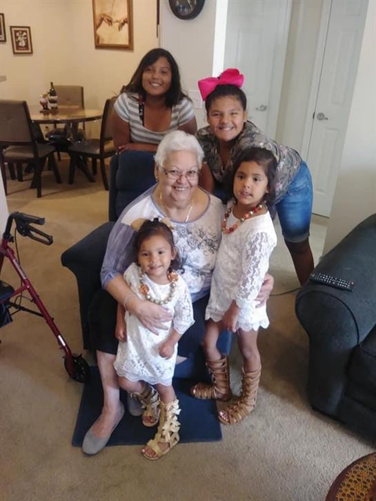 A joyful family moment with four children and their grandmother, smiling in a warm home.
