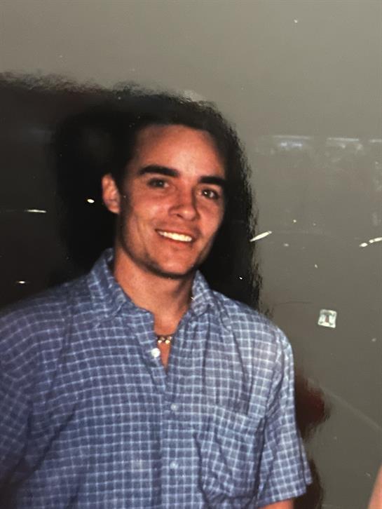 A young man enjoys a lively moment, smiling confidently while attending a gathering.