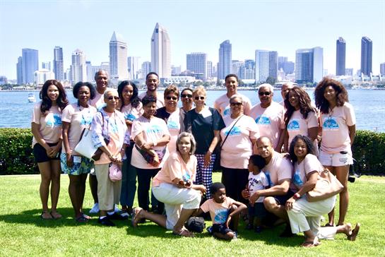 A large group gathers for a family reunion with a vibrant city skyline in the background.