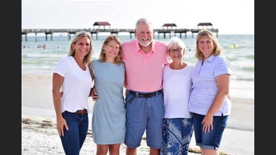 Group of six family members enjoying a happy moment together at the beach under bright sunlight.