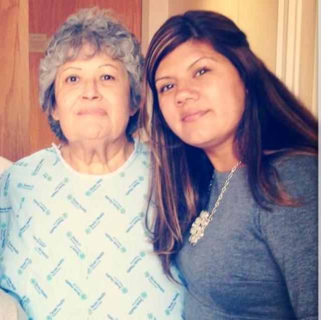 Smiling woman poses with her grandmother, sharing a warm moment in a domestic environment.