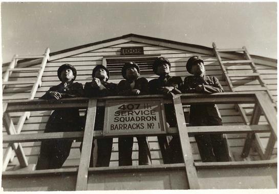 Five soldiers on a balcony at the 407th Service Squadron showcase military camaraderie.