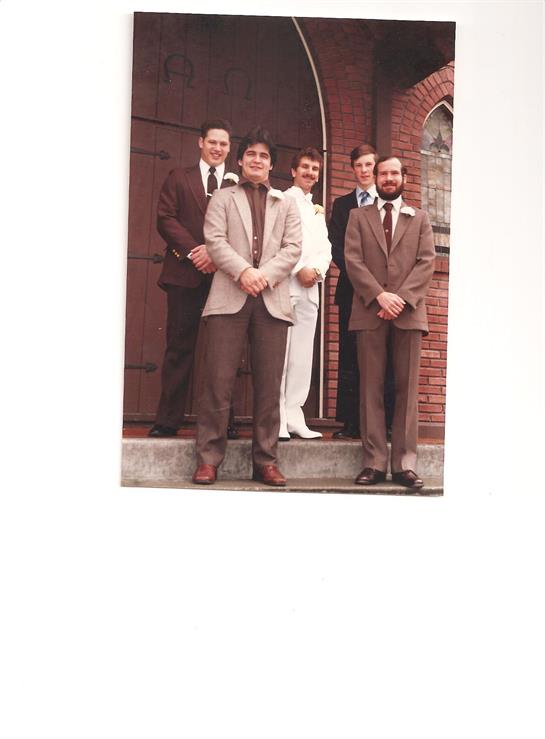 Men dressed in formal attire stand together, smiling, showcasing the joy of a wedding celebration.