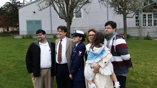 Group of family members poses together outside, celebrating a special event during daylight.
