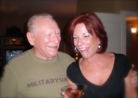 Two people share laughter and drinks at a relaxed social event in the evening light.