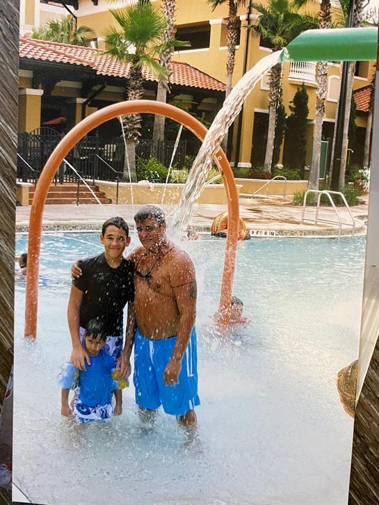 Family plays joyfully in the pool, enjoying water splashes and laughter at a sunny resort.