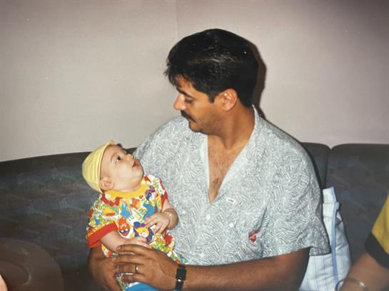A man shares joyful moments with his smiling baby on the sofa.