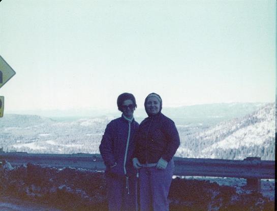 Two friends in warm clothes enjoy a chilly mountain overlook together.