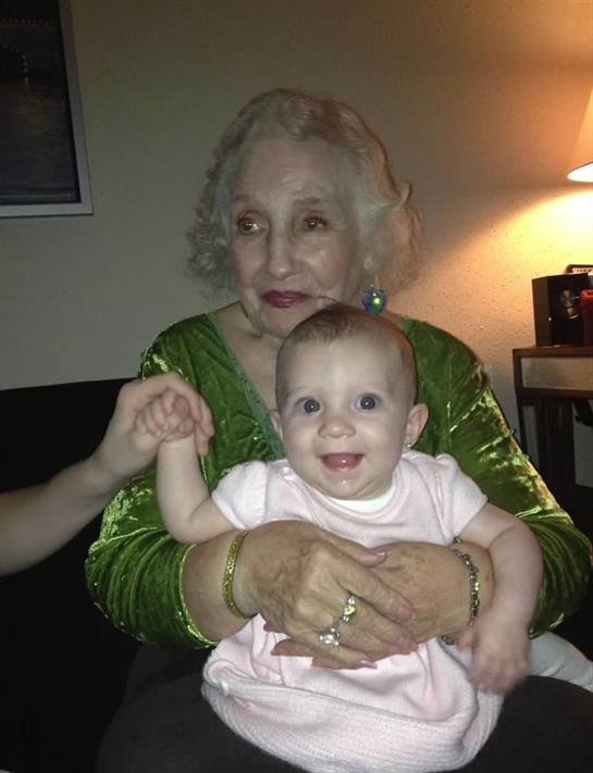 A joyful elderly woman embraces a smiling baby in a warm family setting at night.