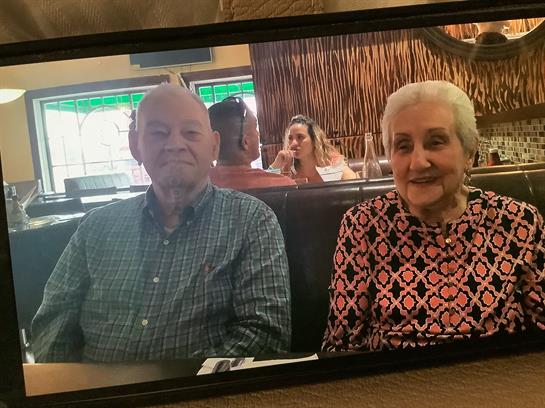 An elderly couple smiles and enjoys their meal at a restaurant.