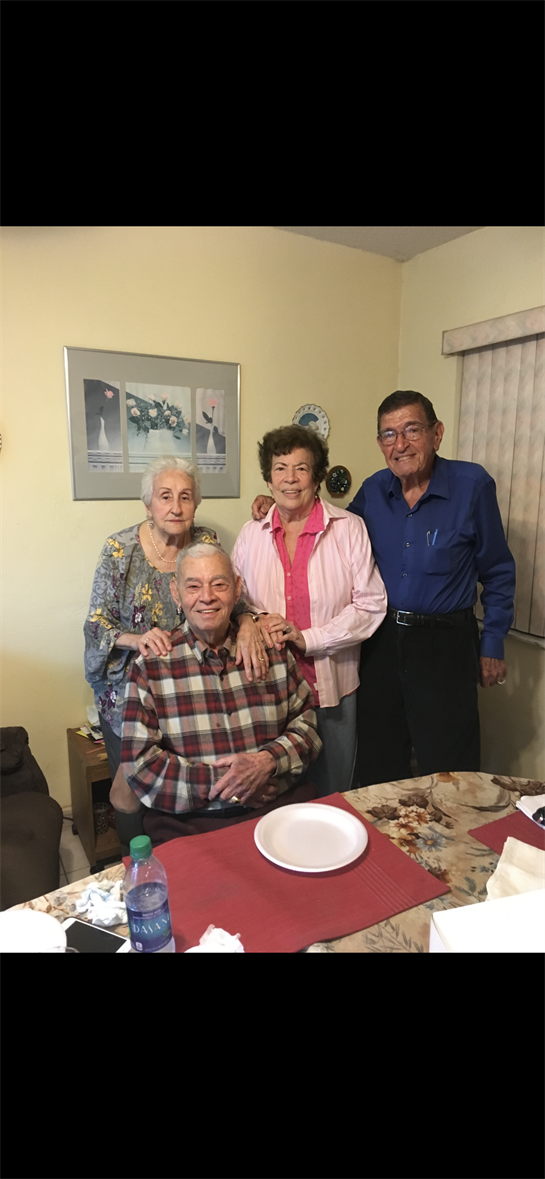 Four elderly friends enjoy quality time together, smiling and posing at a small gathering.