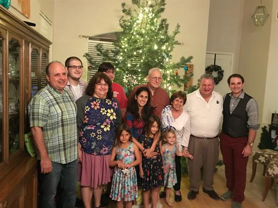 Family members pose together joyfully in a warm setting decorated for Christmas.