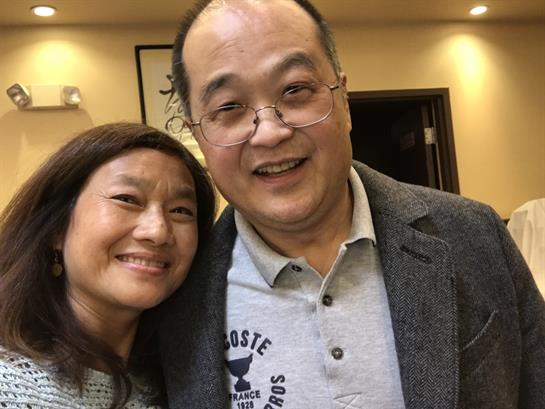 A joyful couple takes a selfie together, smiling widely at a social gathering in a cozy setting.