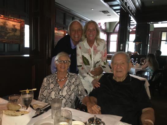 Four family members smiling and enjoying each other's company in a warm restaurant setting.