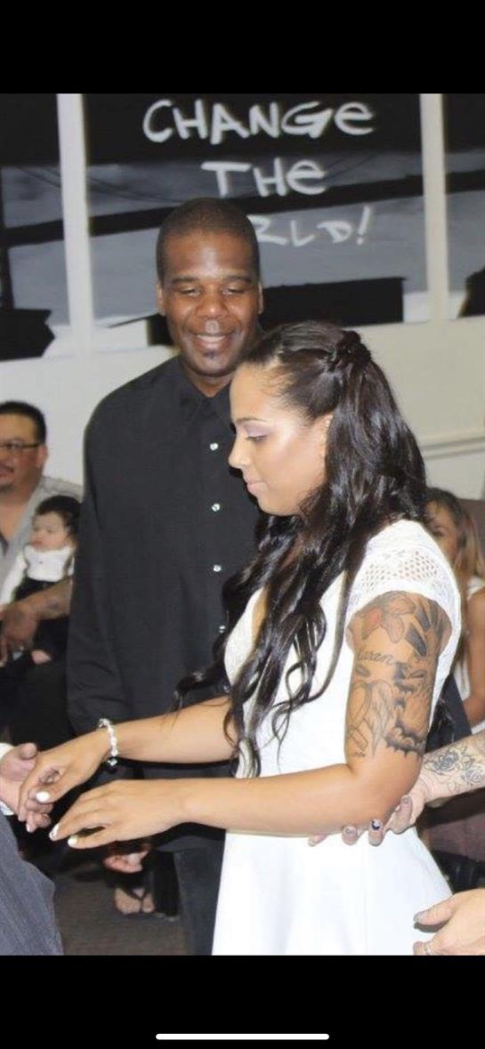 A couple engages in a joyful moment at a festive gathering surrounded by family and friends.