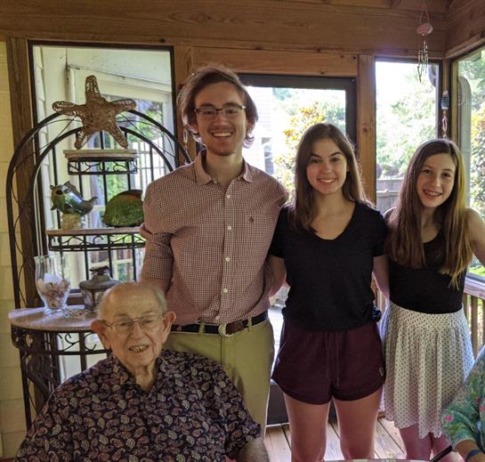 Four family members smile in a warm living room, sharing a joyful moment in the afternoon light.